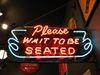 sign reads "please wait to be seated"
