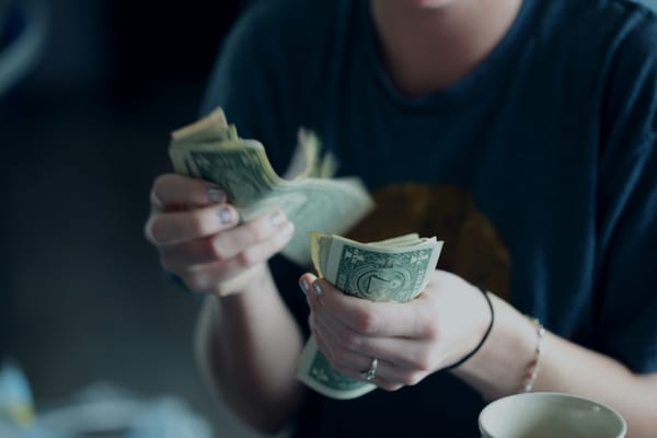 Woman counting dollar bills. Photo by Alexander Grey on Unsplash